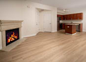 Thumbnail 31 of 36 - A living room with a fireplace and a kitchen area in the background.