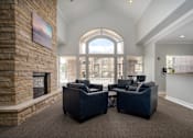 Thumbnail 4 of 36 - A living room with a stone fireplace and two black sofas.