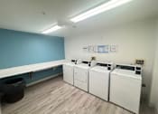 Thumbnail 2 of 6 - A laundry room with a blue wall and laundry machines.