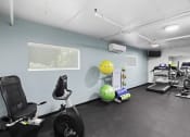 Thumbnail 16 of 20 - Fitness Facilities with exercise equipment like stationary bike and exercise balls with light blue walls and a window at King Arthurs Court, Seattle, WA, 98125