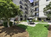 Thumbnail 7 of 20 - Resident Outdoor Lounge Space with a patio and picnic table with umbrella at King Arthurs Court, Seattle, Washington