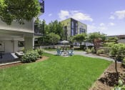 Thumbnail 6 of 20 - Green grassy area with a patio table and chairs at King Arthurs Court, Seattle, Washington