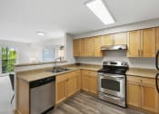 Thumbnail 18 of 22 - a kitchen with wooden cabinets and stainless steel appliances at Villaggio Apartment Homes, Tacoma, 98402