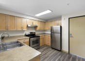 Thumbnail 22 of 22 - a kitchen with wooden cabinets and stainless steel appliances at Villaggio Apartment Homes, WA 98402