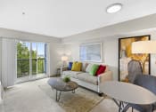 Thumbnail 19 of 22 - a carpeted living room with a couch, table, and a sliding glass door at Villaggio Apartment Homes, Tacoma, Washington 98402