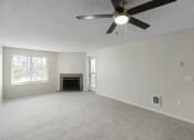 Thumbnail 9 of 19 - a living room with a fireplace, cozy carpeting, oversized windows, and a ceiling fan at Willows Court Apartment Homes, Seattle, WA