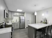 Thumbnail 12 of 19 - an open kitchen with a large island, plank flooring, and stainless steel appliances at Willows Court Apartment Homes, Seattle