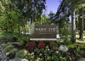 Thumbnail 1 of 18 - Park 201 Welcome Sign with Expertly Manicured Flowers and Trees at Park 210 Apartment Homes, Edmonds, Washington