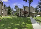 Thumbnail 4 of 18 - Apartment Buildings Surrounded by Grassy Area with Trees at Park 210 Apartment Homes, Washington, 98026