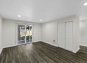 Thumbnail 12 of 18 - Large Open Floor Living Space with Dark Plank Flooring and Wide Sliding Glass Doors Leading Outside at Park 210 Apartment Homes, Edmonds, WA
