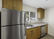 Thumbnail 16 of 18 - Kitchen with Wooden Cabinets and a Stainless Steel Refrigerator at Park 210 Apartment Homes, Edmonds, WA
