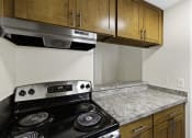 Thumbnail 9 of 18 - A Kitchen with Wood Cabinets and a Stove Top Oven at Park 210 Apartment Homes, Edmonds, WA