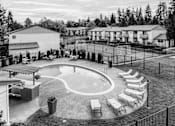 Thumbnail 23 of 23 - a black and white photo of an outdoor pool with chairs at Pinewood Square Apartment Homes, Lynnwood, WA, 98036