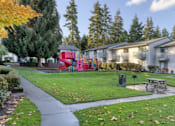 Thumbnail 6 of 23 - a yard with a picnic table and a red slide in front of houses at Pinewood Square Apartment Homes, Lynnwood, WA, 98036