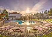Thumbnail 1 of 23 - Glistening Swimming Pool at Sunset with lounge chairs and Meticulous Landscaping at Pinewood Square Apartment Homes, Lynnwood, WA