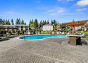 Thumbnail 4 of 23 - Sparkling Outdoor Pool and Hot Tub with Trees in the Background at Pinewood Square Apartment Homes, Lynnwood, Washington 98087