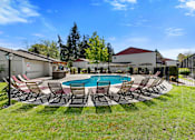 Thumbnail 3 of 23 - Cool Blue Swimming pool with Lounge Chairs and Grassy Area at Pinewood Square Apartment Homes, Lynnwood