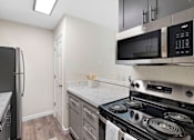 Thumbnail 20 of 23 - Modern Kitchen with Stainless Steel Appliances, White Countertops, and Plank Flooring at Pinewood Square Apartment Homes, Lynnwood, Washington 98087