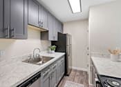 Thumbnail 17 of 23 - Modern Kitchen with Plank Flooring, Overhead Beam Lighting, and Dark Cabinetry at Pinewood Square Apartment Homes, Washington, 98087
