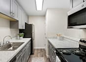 Thumbnail 14 of 23 - Kitchen With Chic Finishes like Stainless Steel Appliances, Plank Flooring, and Elegant Cabinetry at Pinewood Square Apartment Homes, Lynnwood, 98087