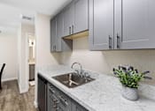 Thumbnail 16 of 23 - a kitchen with gray cabinets and a stainless steel sink at Pinewood Square Apartment Homes, Washington
