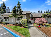 Thumbnail 12 of 23 - Stone Walkway Path Leading to Welcome Building  with Parking Spots in Front at Pinewood Square Apartment Homes, Lynnwood, 98087