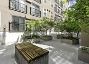 Thumbnail 14 of 27 - a courtyard with a wooden bench and trees in front of  Sir Gallahad Apartment Homes, Washington, 98004
