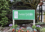 Thumbnail 7 of 30 - Swiss Gables Property Sign with Multicolor Flowers Underneath it at Swiss Gables Apartment Homes, Kent