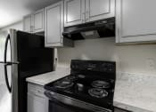 Thumbnail 28 of 30 - a kitchen with white cabinets and black appliances at Swiss Gables Apartment Homes, Kent, 98032