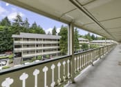 Thumbnail 5 of 30 - a balcony with a white fence and a large building in the background at Swiss Gables Apartment Homes, Kent, 98032