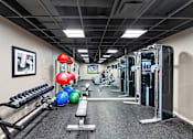 Thumbnail 22 of 23 - A gym with a variety of equipment including a bench, weights, and a rowing machine at MainCentre, Northville