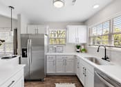 Thumbnail 4 of 24 - A modern kitchen with white cabinets and a stainless steel refrigerator at Briarcliff Village, Michigan, 48390