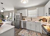 Thumbnail 16 of 24 - A modern kitchen with white cabinets and stainless steel appliances at Briarcliff Village, Michigan, 48390