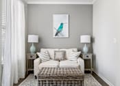 Thumbnail 8 of 20 - A living room with a white couch, a wicker coffee table, and a painting of a bird on the wall at Park West, Canton, 48187
