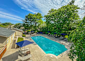 Thumbnail 17 of 22 - Pool and patio with chairs and umbrellas at Amberly Apartments, West Bloomfield, 48322