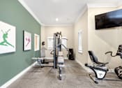 Thumbnail 16 of 18 - A home gym with a green wall and exercise equipment.