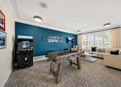 Thumbnail 28 of 34 - a game room with a foosball table and a video game at Cidermill Village Apartments in Rochester Hills, MI 