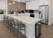 Thumbnail 22 of 34 - a large white kitchen with a large island and stainless steel appliances at Cidermill Village Apartments in Rochester Hills, MI 