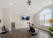 Thumbnail 27 of 34 - a home gym with exercise equipment and a window at Cidermill Village Apartments in Rochester Hills, MI 
