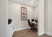 Thumbnail 31 of 34 - A room with a chair, a desk, and two pictures on the wall at Cidermill Village Apartments in Rochester Hills, MI 