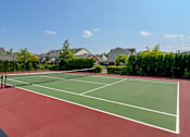 Thumbnail 33 of 34 - A tennis court with a net and green court surface at Cidermill Village Apartments in Rochester Hills, MI 