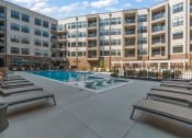 Thumbnail 18 of 19 - an outdoor pool with chaise lounge chairs and a building in the background  at The Griffin Royal Oak, Royal Oak, 48067