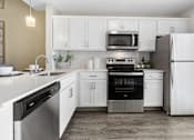 Thumbnail 16 of 26 - A modern kitchen with white cabinets and stainless steel appliances.