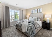 Thumbnail 19 of 26 - A bedroom with a large bed and a window with curtains.