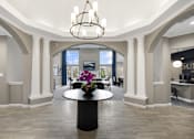 Thumbnail 17 of 23 - A large, elegant room with a chandelier, a table with flowers, and a reception desk.
