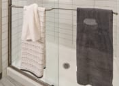 Thumbnail 12 of 19 - a small bathroom with white tiles and a glass shower door at The Griffin Royal Oak, Royal Oak, MI