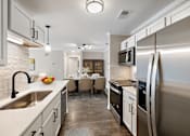 Thumbnail 11 of 34 - a kitchen and dining room with stainless steel appliances and a sink at Cidermill Village, MI