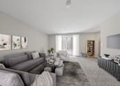Thumbnail 9 of 17 - A living room with grey couches and a coffee table.