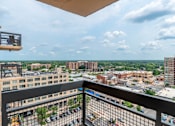 Thumbnail 25 of 25 - A balcony overlooks a parking lot and buildings.