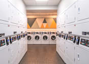 Thumbnail 13 of 25 - A row of washing machines are lined up in a laundromat.